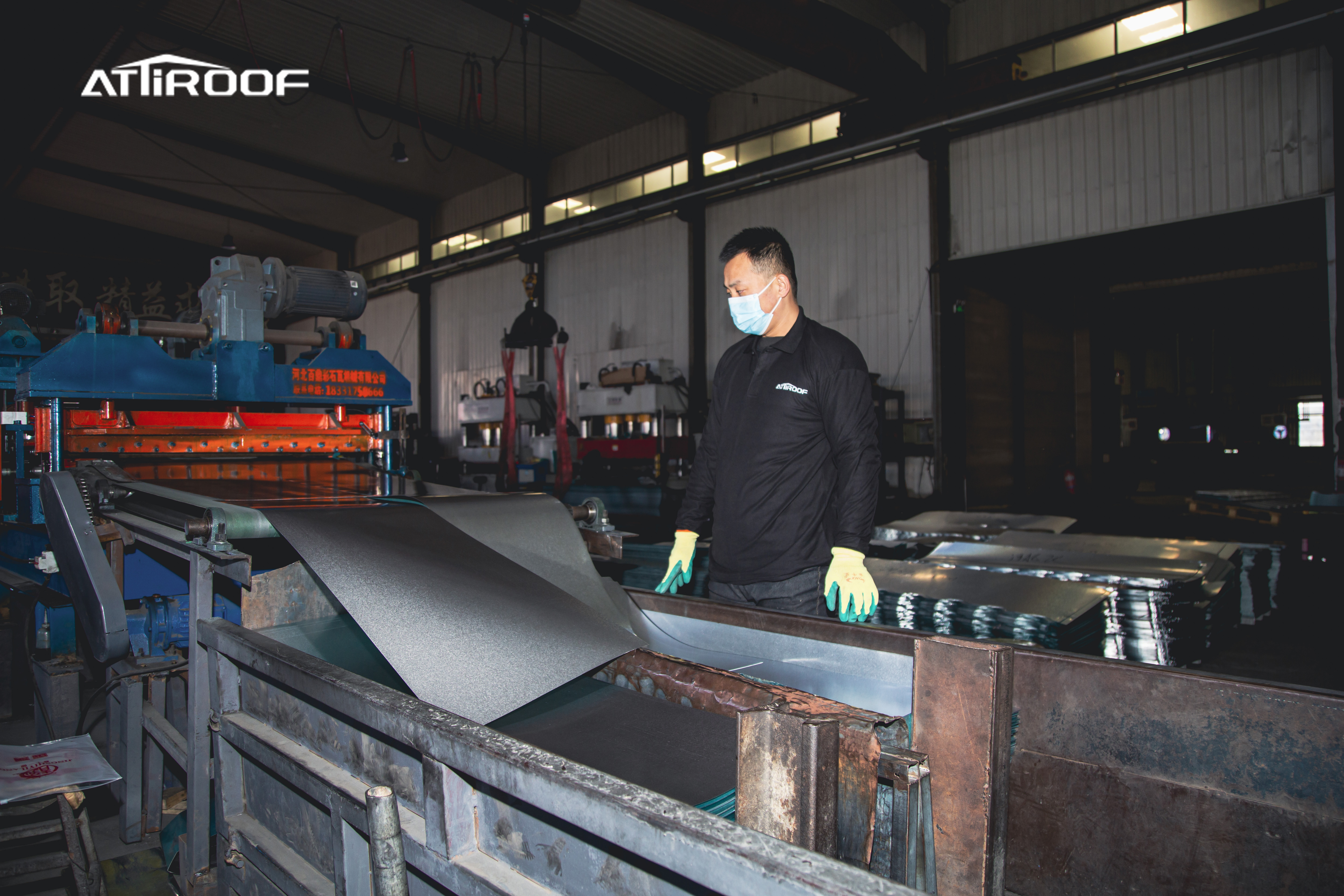 Worker in a modern factory monitoring the production of synthetic resin roof tiles with energy-efficient technology.