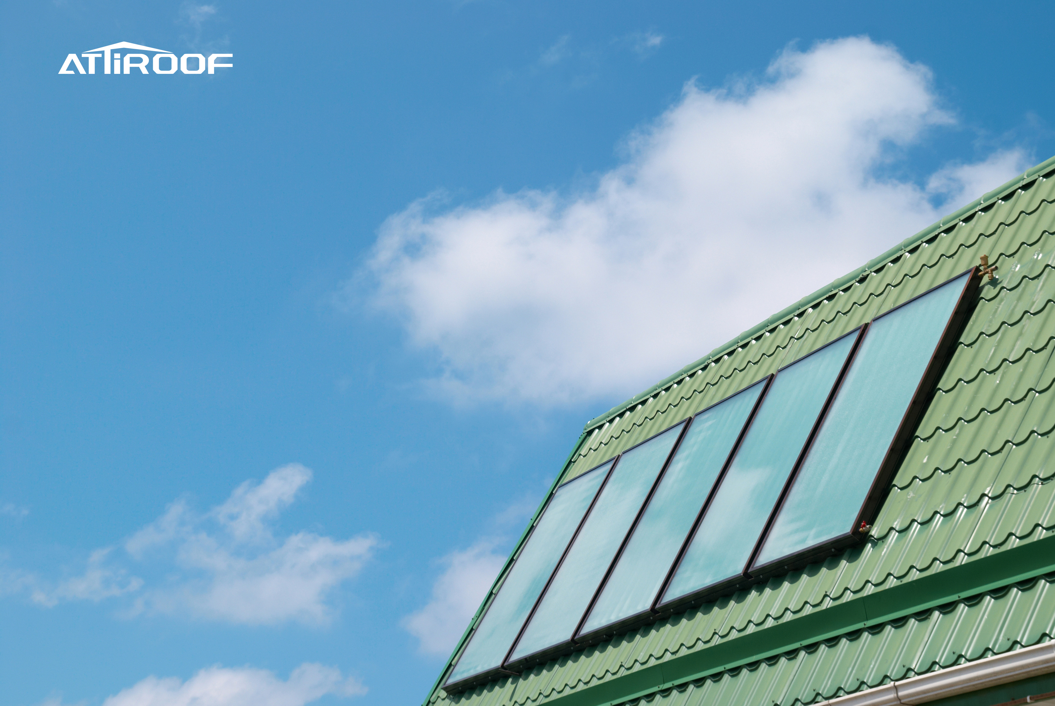 Green synthetic resin roof tiles on a building meeting green construction standards against a blue sky with clouds.