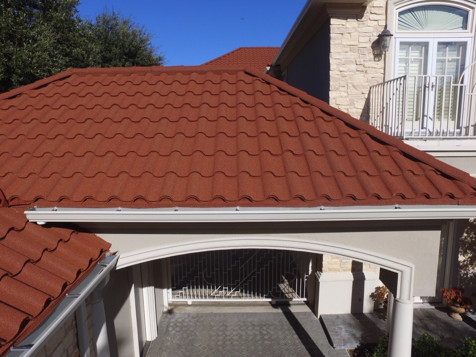 The house has a stone-coated metal roof. It's covered with bright, well-maintained, red stone tiles. They show the house is new and sturdy.