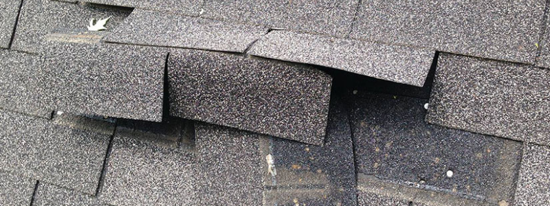 Damaged stone-coated metal roof tiles with bent and dislodged sections, illustrating the need for regular maintenance.