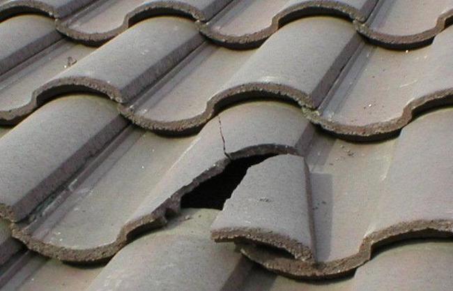 Cracked stone-coated metal roof tile illustrating the need for timely repairs to prevent water damage.