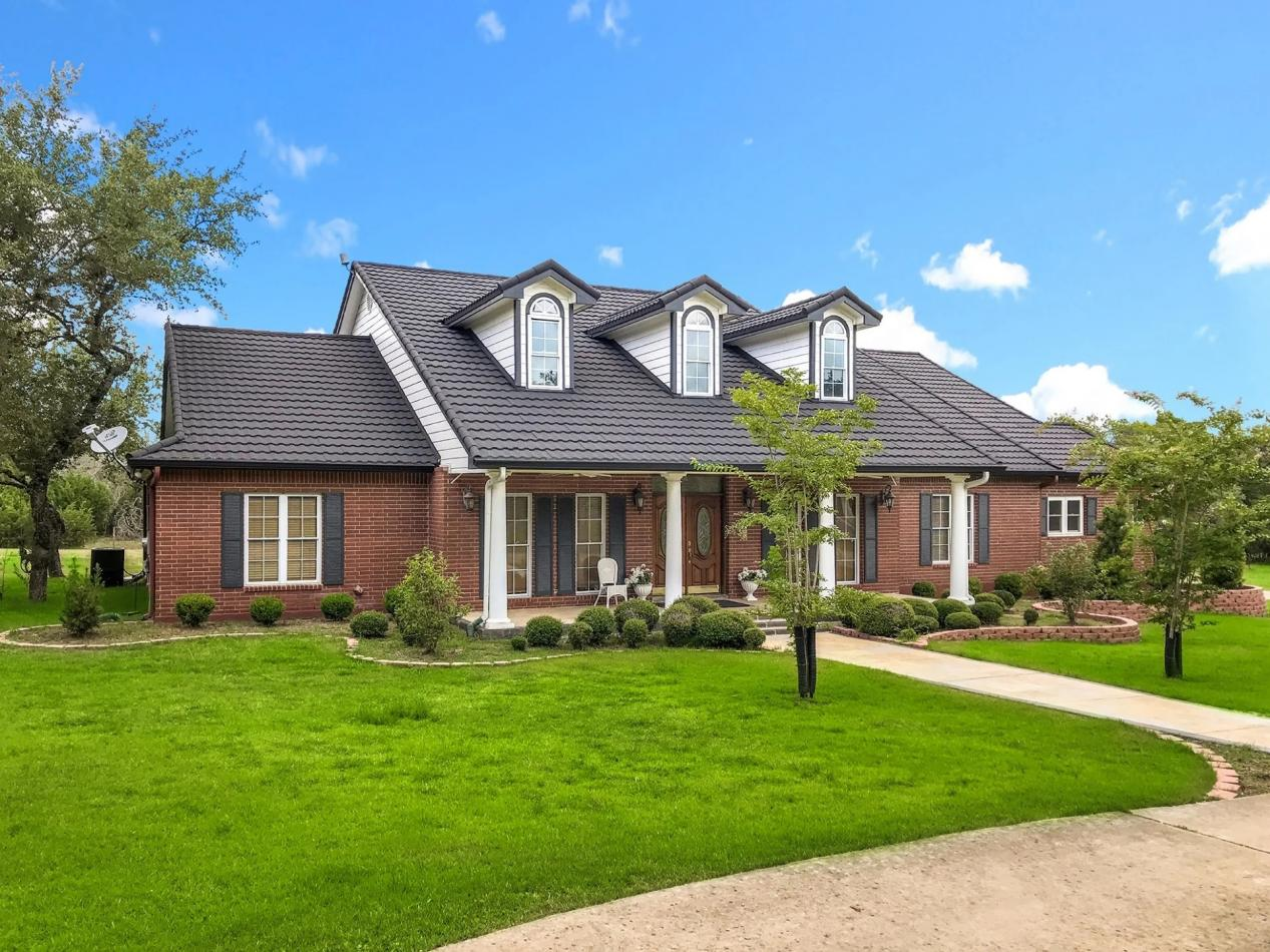 Elegant home featuring dark-colored Roof Tiles Design, complementing the red brick exterior.